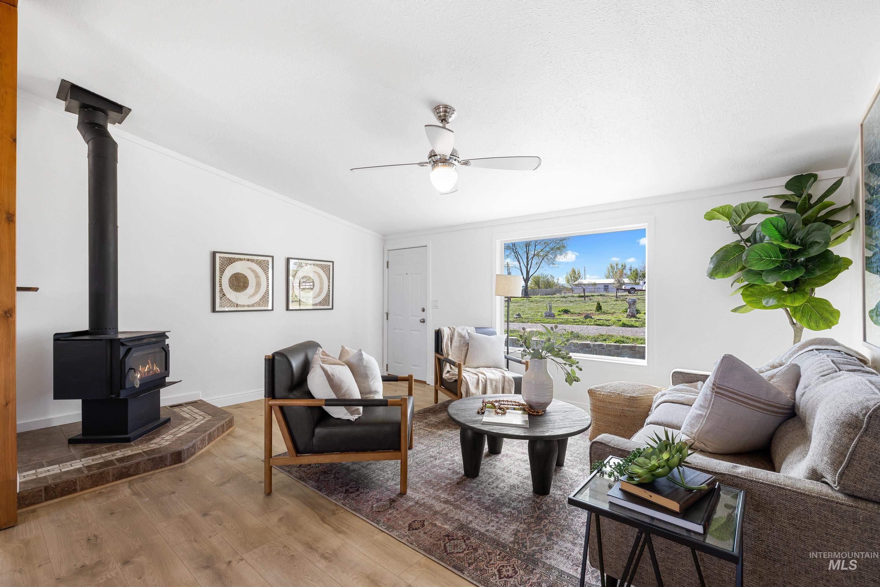 2427 Northside Road Homedale, ID 83628 - Photo 7 of 49 Living room featuring a wood stove, wood finished floors, a ceiling fan, crown molding, and vaulted ceiling