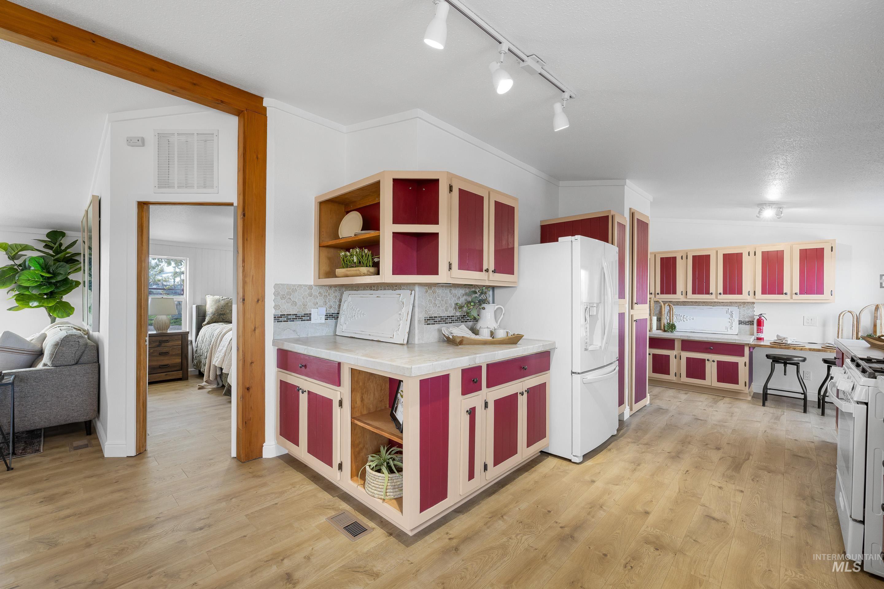 2427 Northside Road Homedale, ID 83628 - Photo 9 of 49 Kitchen featuring open shelves, vaulted ceiling, white appliances, decorative backsplash, and dual tone cabinets