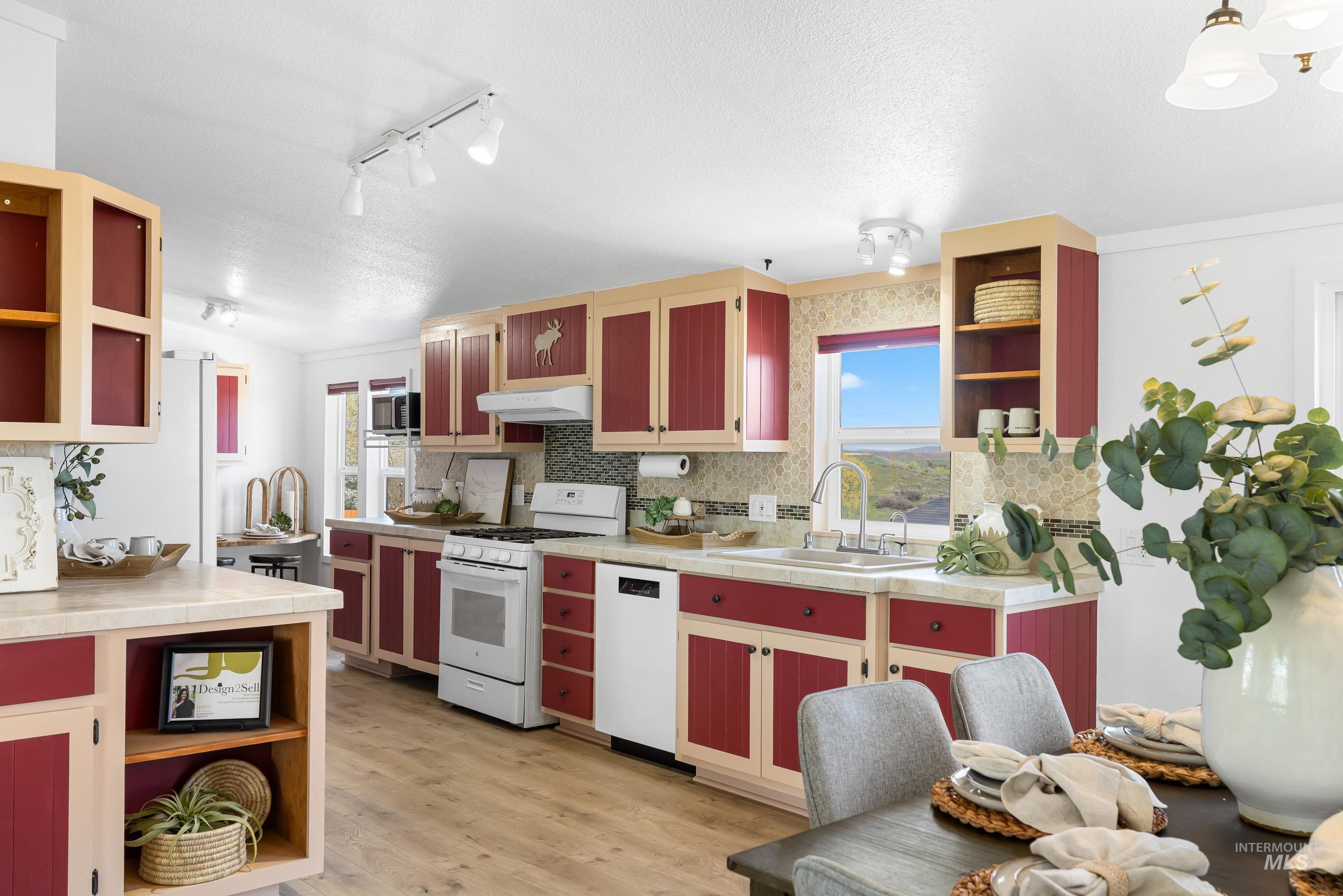 2427 Northside Road Homedale, ID 83628 - Photo 10 of 49 Dual tone kitchen featuring open shelves, white appliances, light wood-style floors, healthy amount of natural light, and dual tone cabinetry