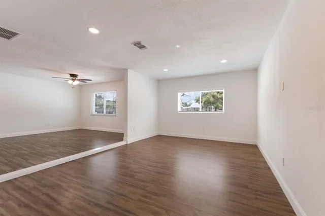 an empty room with wooden floor cabinet and windows