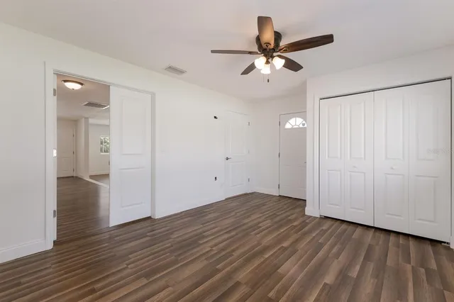 a view of a room with wooden floor and a ceiling fan