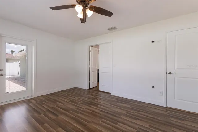 an empty room with wooden floor and windows