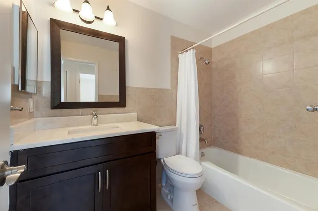 a bathroom with a bathtub sink vanity mirror and toilet