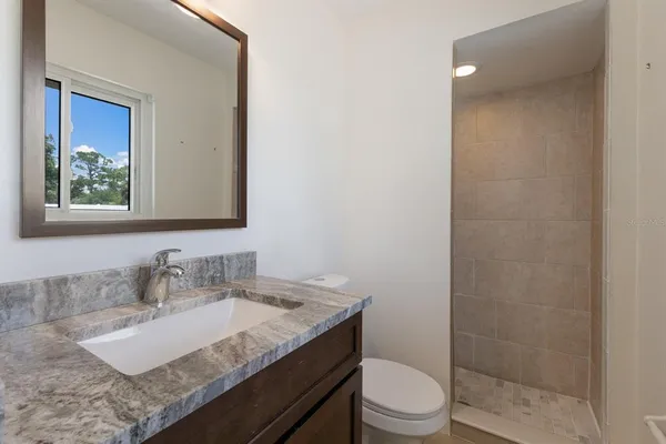 a bathroom with a granite countertop sink a toilet and a mirror