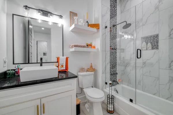 a bathroom with a bathtub shower sink vanity and toilet