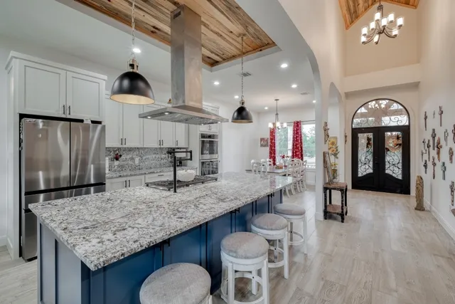 a kitchen with stainless steel appliances granite countertop a table chairs and a refrigerator