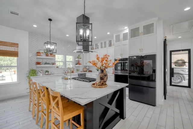 a kitchen with stainless steel appliances granite countertop a sink a stove a refrigerator and island with wooden floor