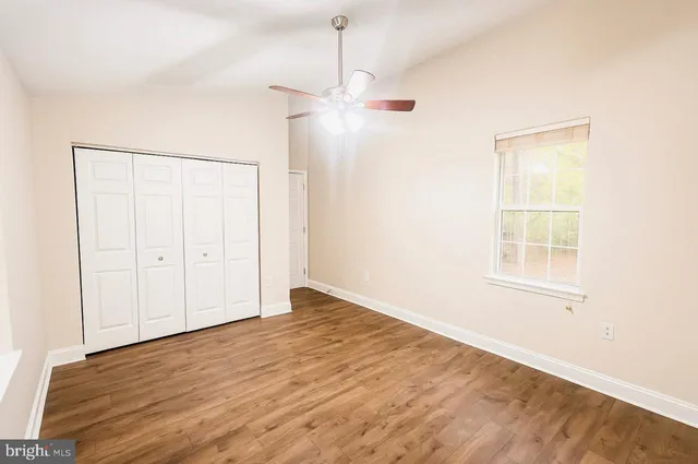 an empty room with wooden floor cabinet and windows