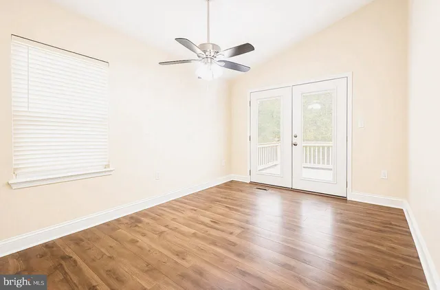 a view of empty room with wooden floor and fan