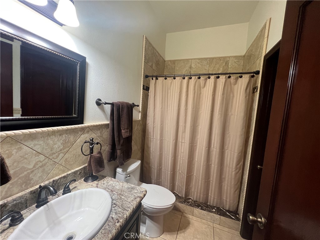 17305 Sage Avenue Riverside, CA 92504 - Photo 15 of 40 a bathroom with a granite countertop sink and a mirror