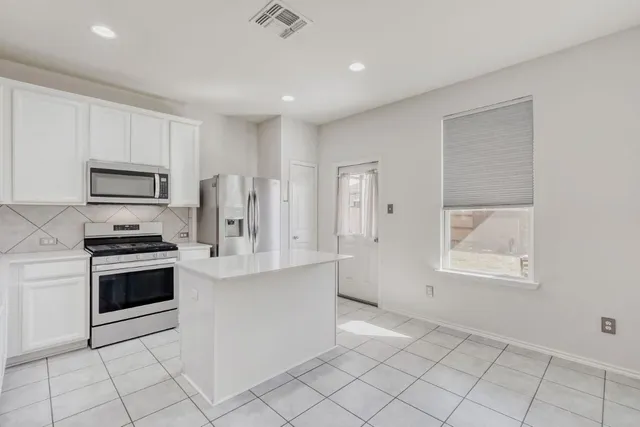 a kitchen with white cabinets and appliances