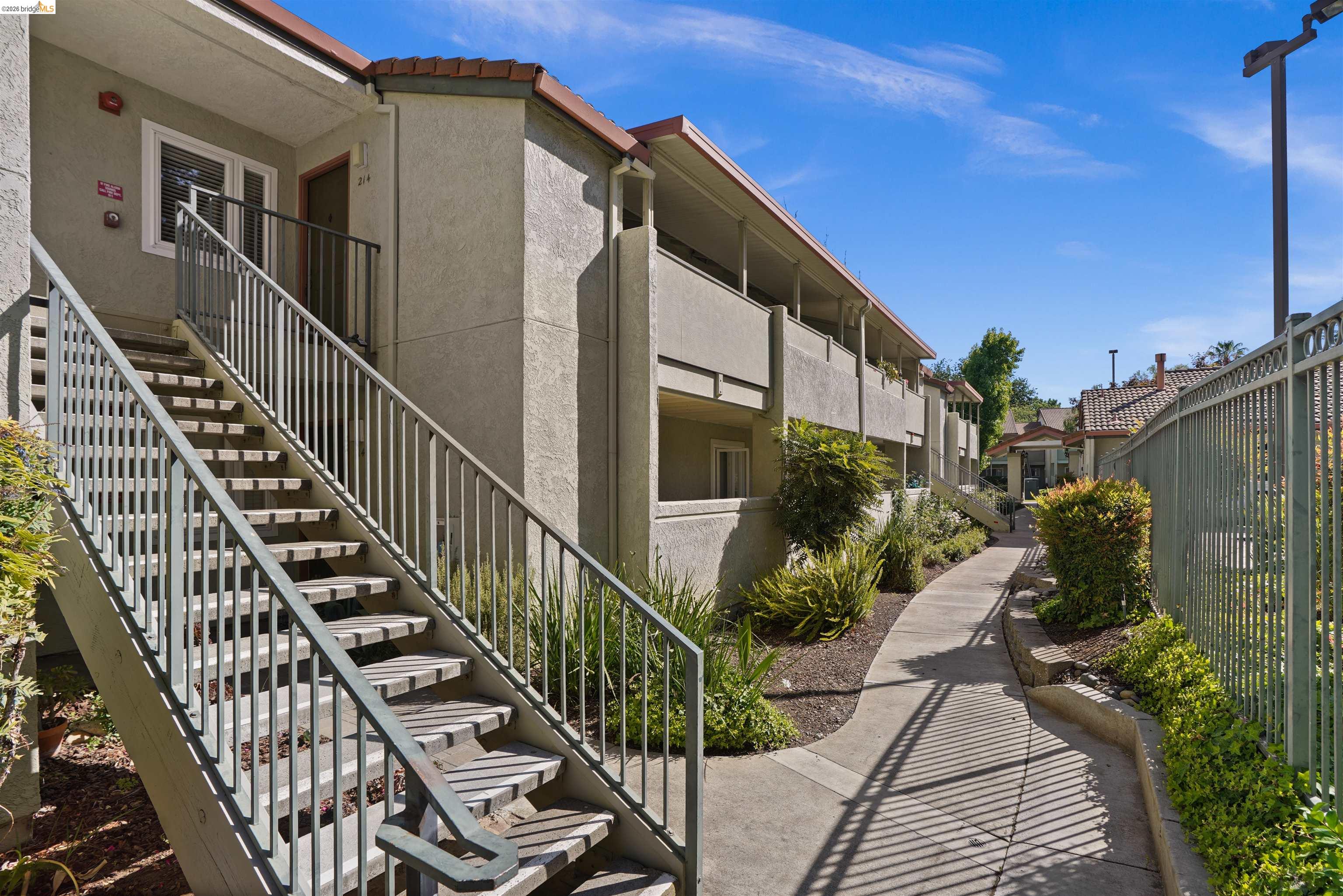 1505 Kirker Pass Road, Unit 214 Concord, CA 94521 - Photo 55 of 55 Apartment building exterior featuring stucco siding, terracotta-style roof tiles, and a concrete walkway