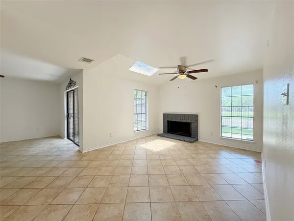 an empty room with windows and fireplace