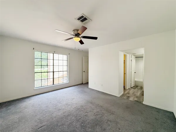 an empty room with ceiling fan and windows
