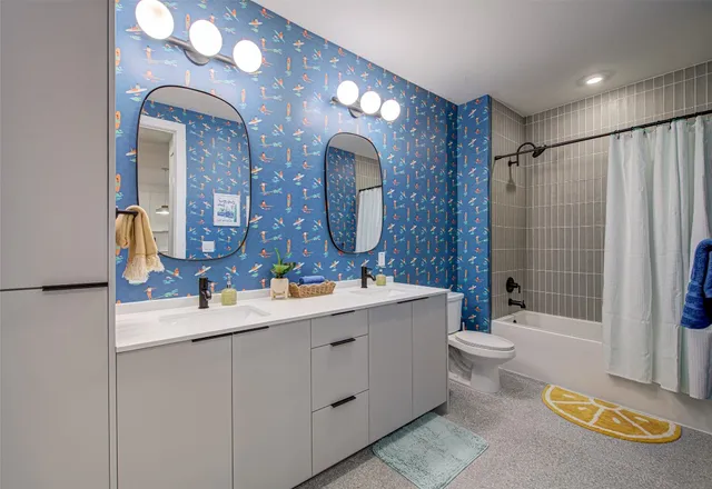 a bathroom with a double vanity sink toilet mirror and bathtub