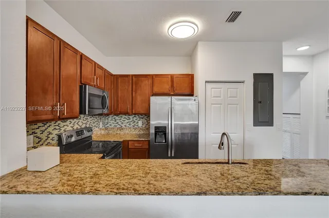 a kitchen with stainless steel appliances kitchen island granite countertop a refrigerator and a stove