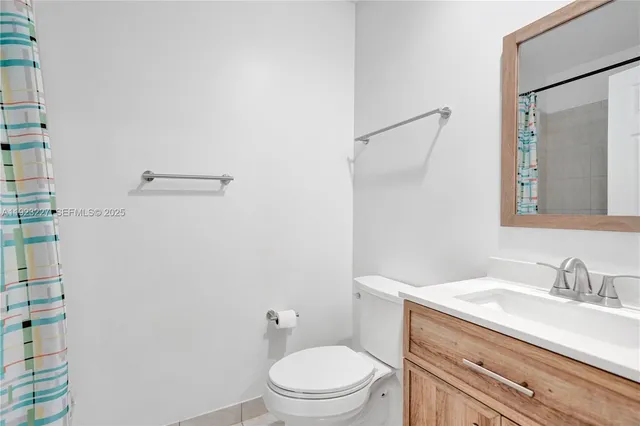 a bathroom with a granite countertop toilet sink and mirror