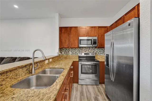 a kitchen with kitchen island granite countertop a sink stove and refrigerator