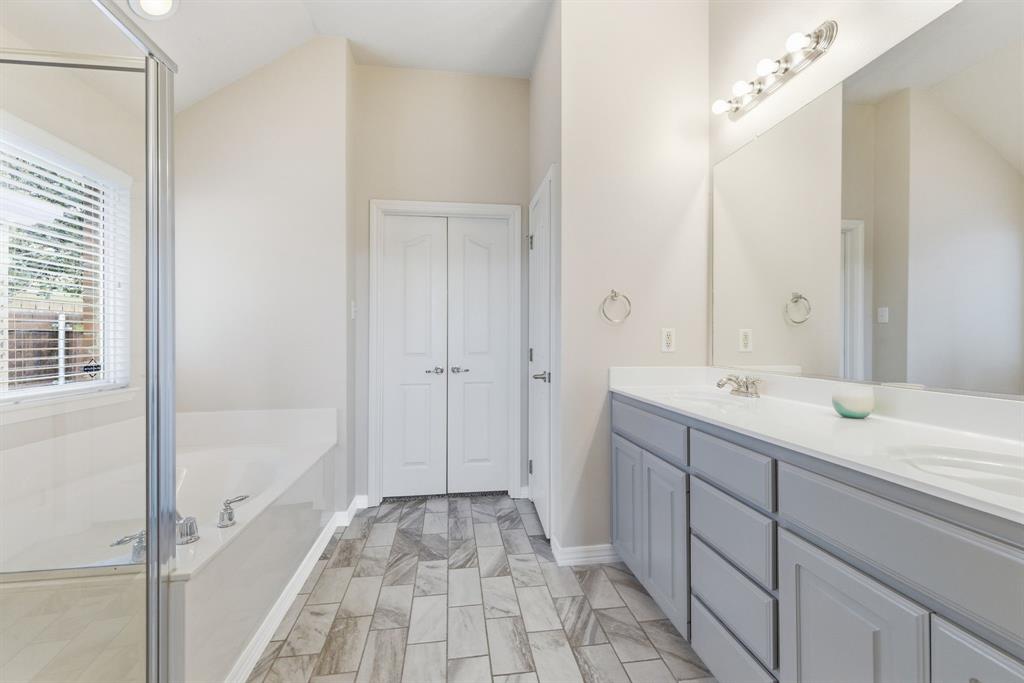 817 Huebner Way Burleson, TX 76028 - Photo 29 of 35 The primary bathroom has been updated with new tile, painted cabinets, and fresh paint. This bathroom has dual sinks, separate shower, garden tub and large walk in closet.