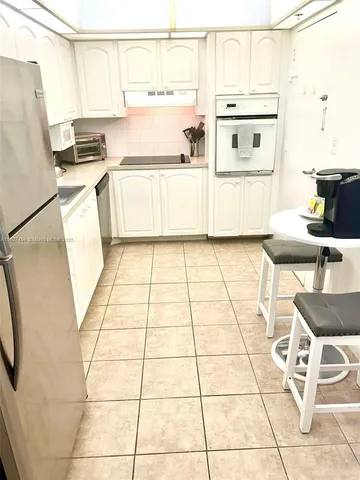 a kitchen with a sink a stove and white cabinets with wooden floor