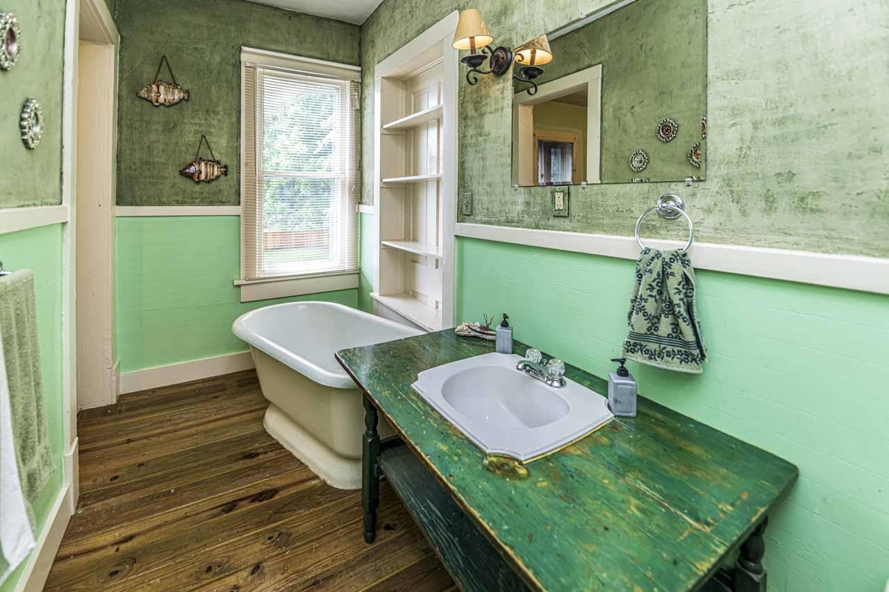 726 South Main Street Covington, TN 38019 - Photo 24 of 40 Bathroom featuring a freestanding clawfoot tub, wood-finish flooring, a window with natural light, a built-in shelving unit, and a vanity with an integrated sink