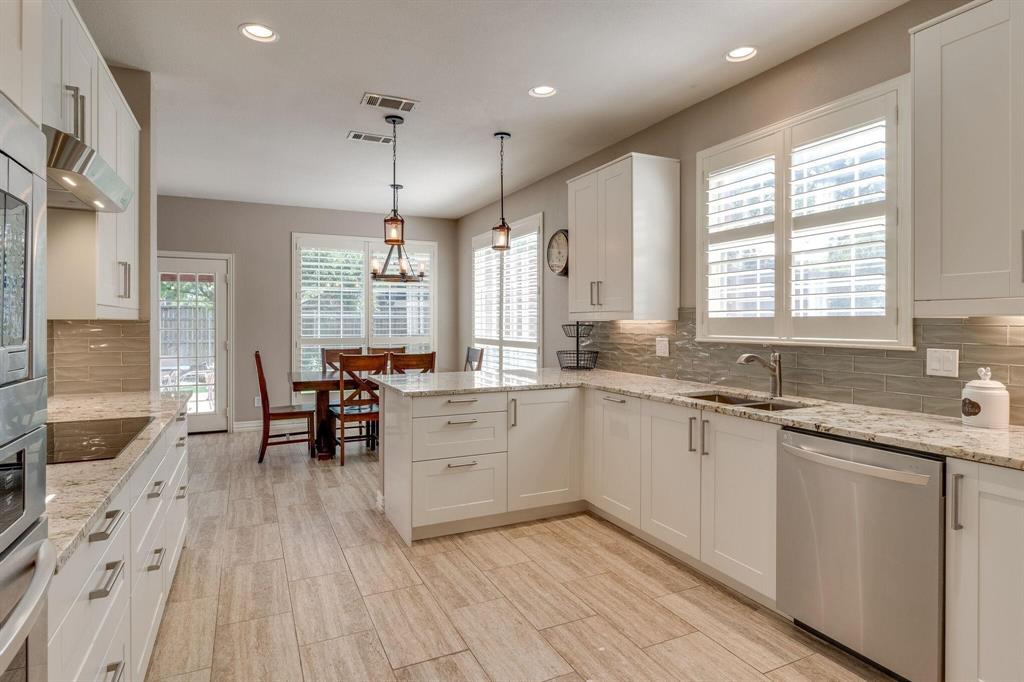 18 Greenleaf Drive Trophy Club, TX 76262 - Photo 14 of 25 a large white kitchen with granite countertop a stove a sink dishwasher a dining table and chairs with wooden floor
