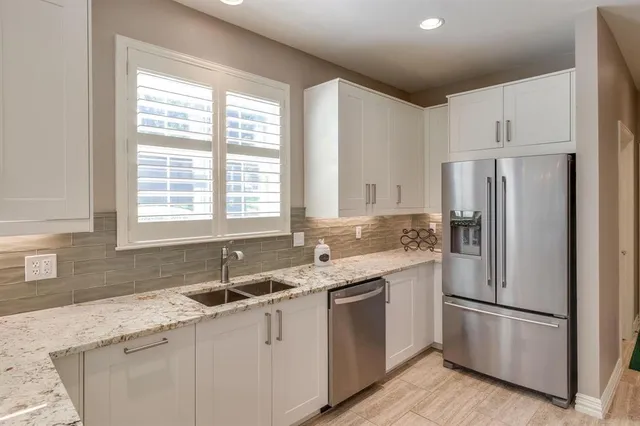a kitchen with granite countertop white stainless steel appliances a sink and a window