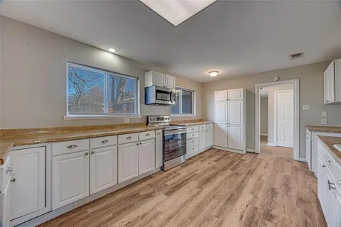 a kitchen with granite countertop a stove top oven sink and cabinets