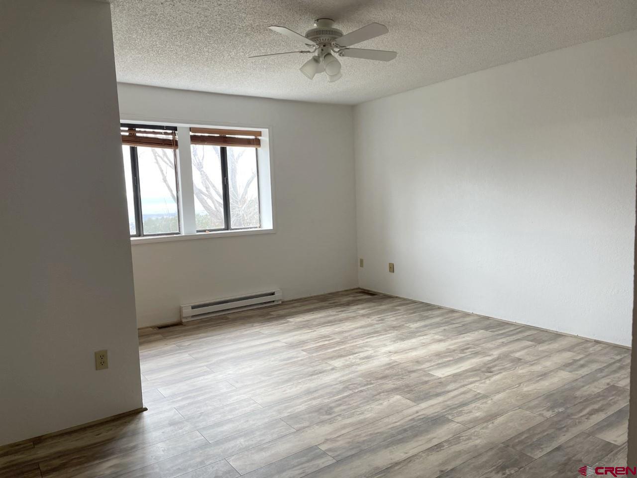 21566 Uintah Road Cedaredge, CO 81413 - Photo 16 of 33 an empty room with wooden floor ceiling fan and windows