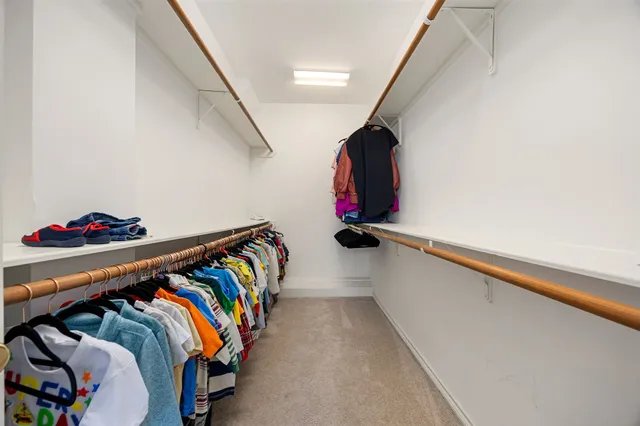 a view of walk in closet with clothes and shoes