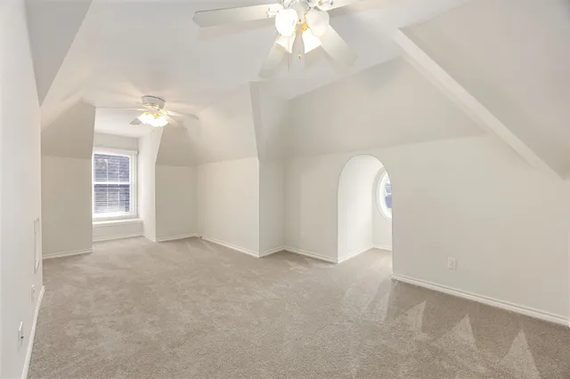 an empty room with a chandelier fan and windows