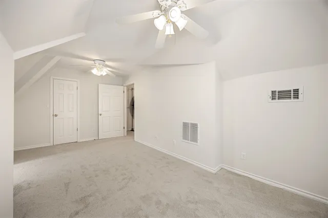 an empty room with chandelier fan and windows