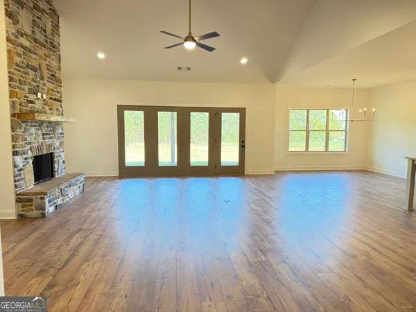 a living room with a fireplace furniture a ceiling fan and a window