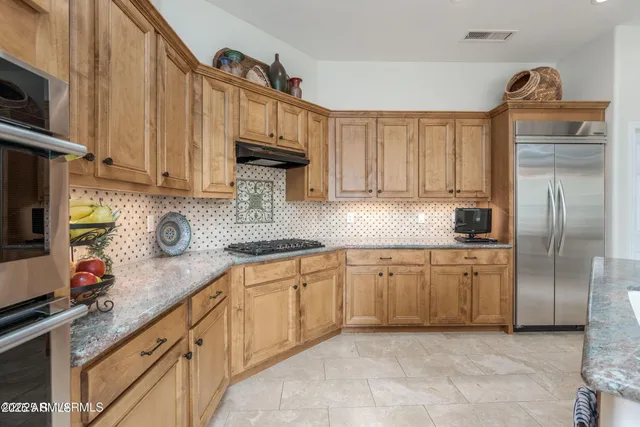 a kitchen with granite countertop a sink a center island stainless steel appliances and cabinets