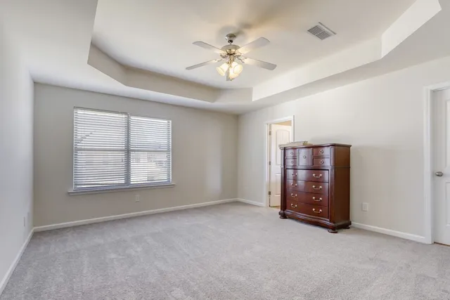 an empty room with windows and ceiling fan