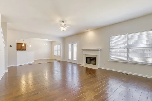 an empty room with wooden floor fireplace and windows