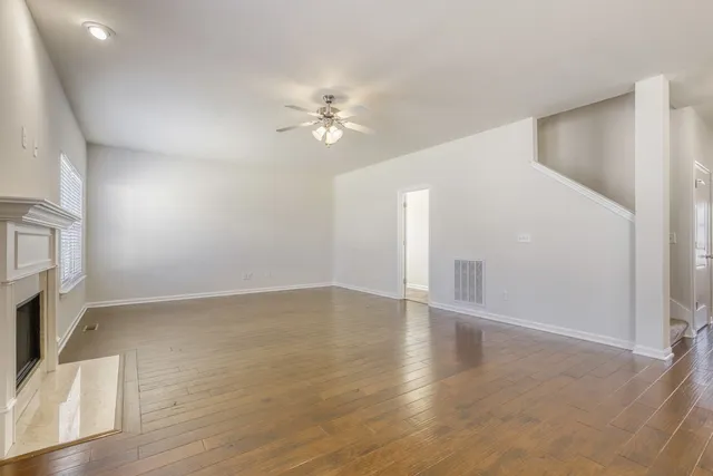 an empty room with wooden floor fan and windows