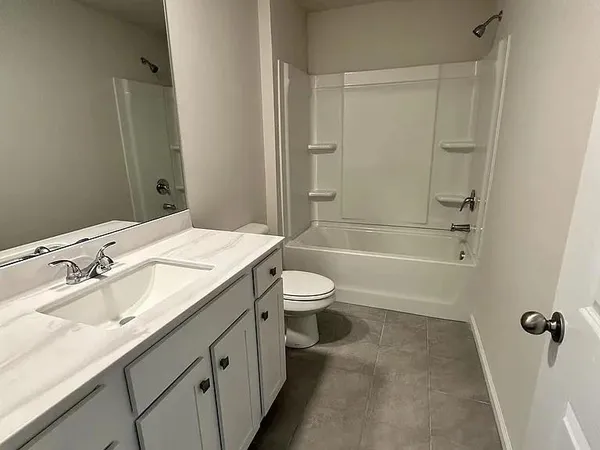 a bathroom with a granite countertop sink a toilet a mirror and shower