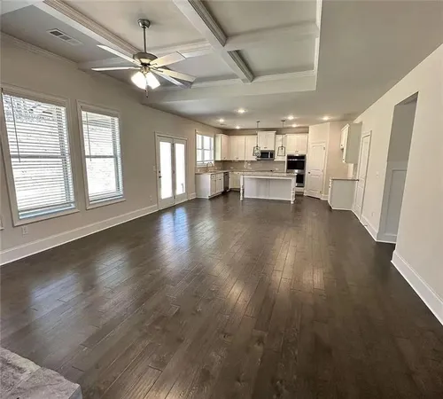 an empty room with wooden floor fan and windows