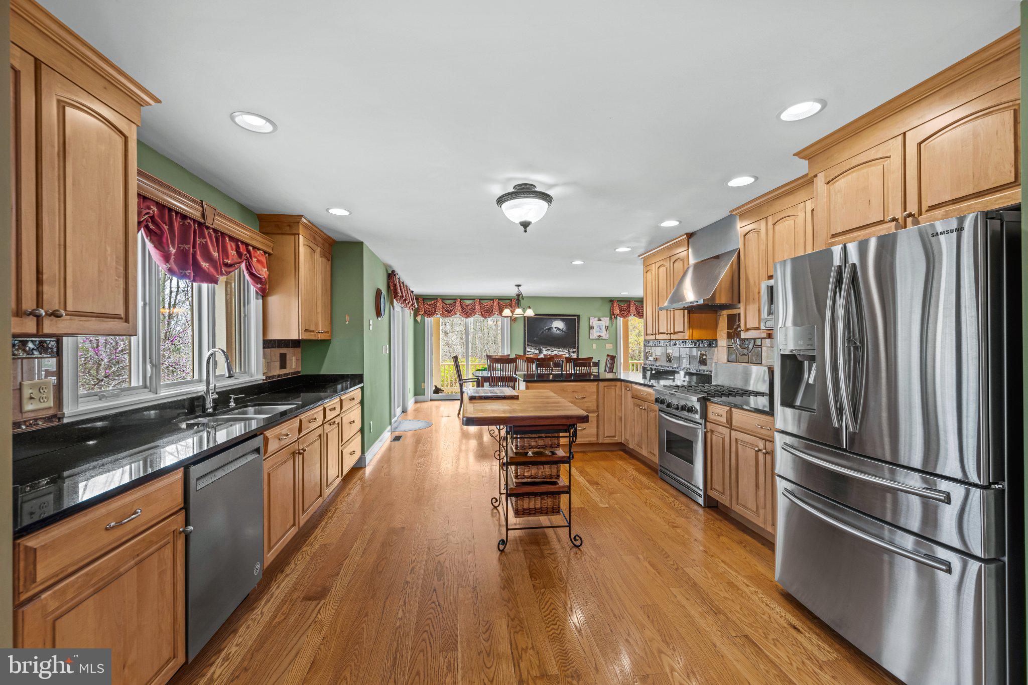 21042 Millers Mill Road Freeland, MD 21053 - Photo 88 of 122 a kitchen with stainless steel appliances a refrigerator a stove top oven a sink dishwasher and a dining table with wooden floor