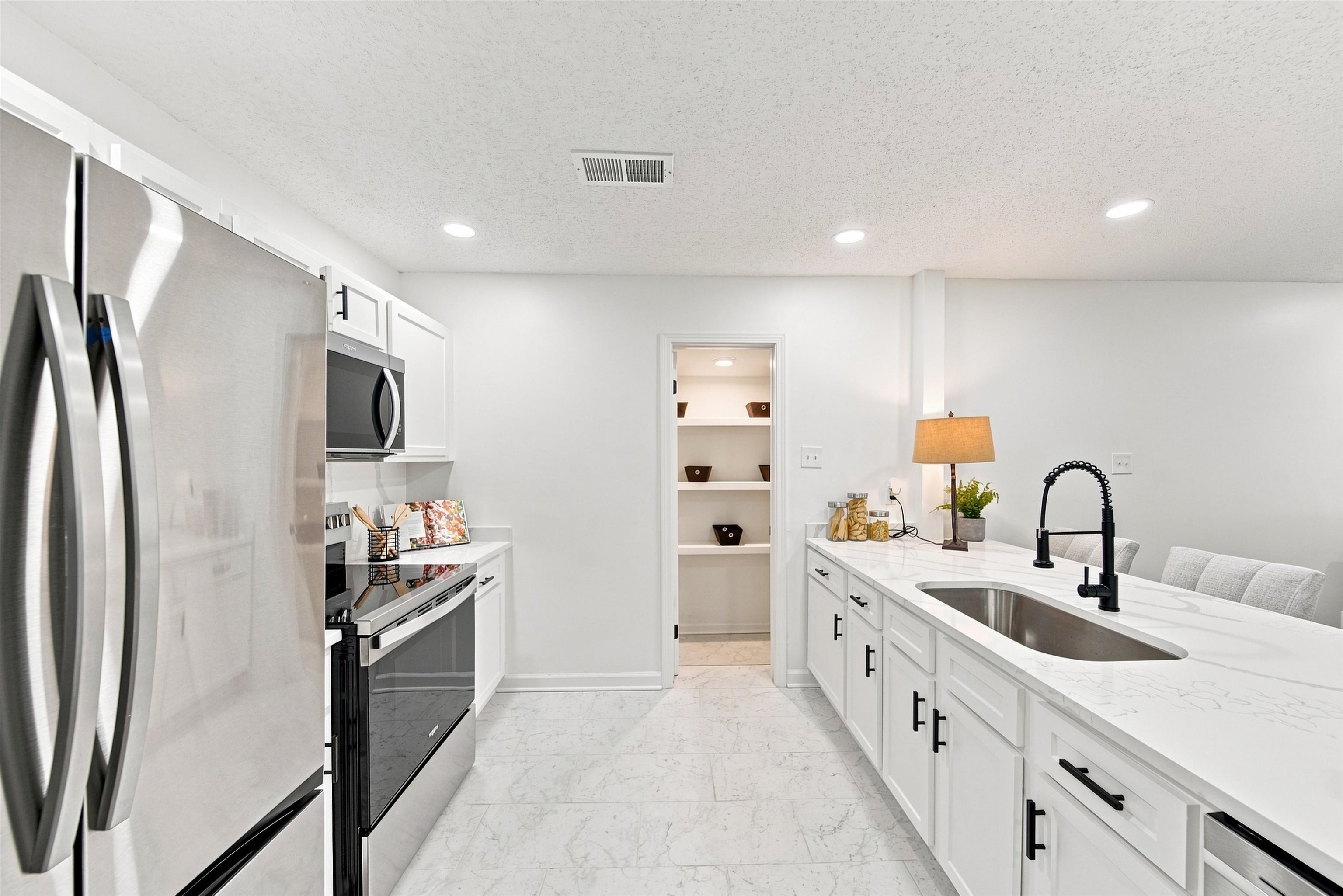 458 Gerald Road Memphis, TN 38122 - Photo 11 of 37 Stainless steel appliances, recessed lighting, white cabinetry with black hardware, stone countertops, and a kitchen island with an undermount sink