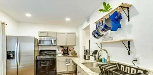 a kitchen with stainless steel appliances granite countertop a sink a stove and a refrigerator