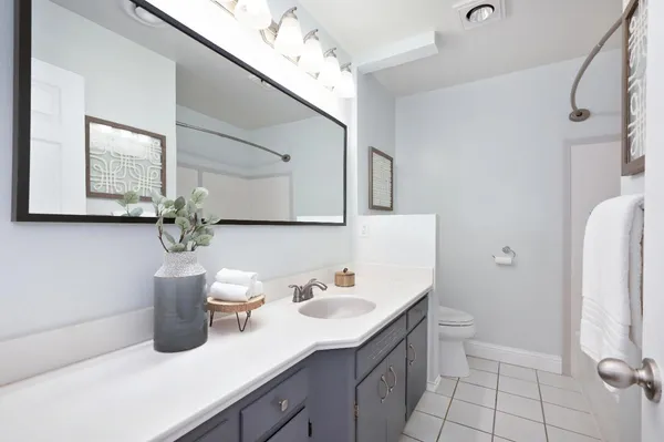a bathroom with a granite countertop sink a toilet and mirror