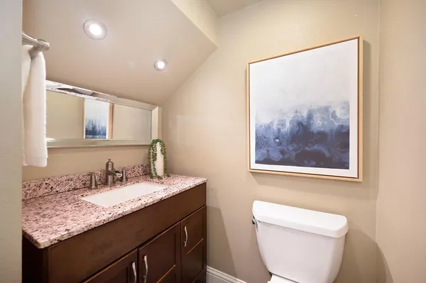 a bathroom with a granite countertop sink a toilet and a mirror