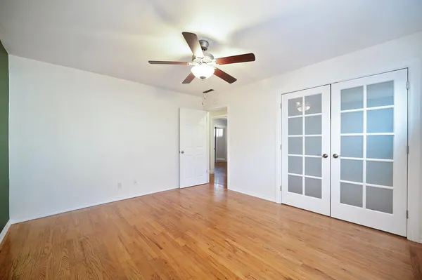 a view of empty room with wooden floor and fan