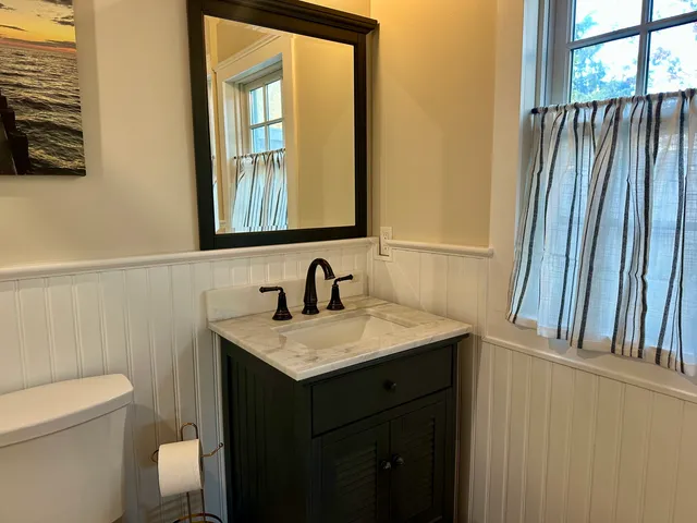 a bathroom with a granite countertop sink toilet and mirror