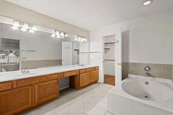 a large bathroom with a double vanity sink a large mirror and a bathtub