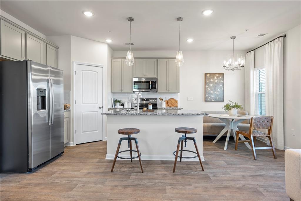 11531 Kimberly Court Hampton, GA 30228 - Photo 12 of 29 a kitchen with stainless steel appliances granite countertop a refrigerator a stove a sink a dining table and chairs with wooden floor