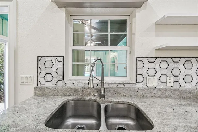 a kitchen with stainless steel appliances granite countertop a stove top oven a sink a dining table and chairs