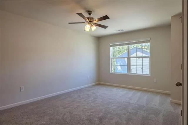 an empty room with ceiling fan and windows